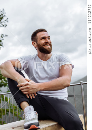 Handsome muscular hunk man looking at mountains from the peak. 114212732
