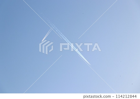 A white plane shining in the deep blue sky, leaving a contrail in the air A white plane shining in the deep blue sky, leaving a contrail in the air 114212844