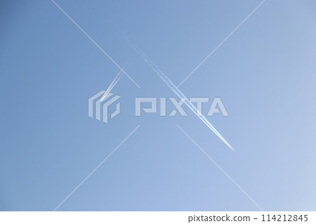 A white plane shining in the deep blue sky, leaving a contrail in the air A white plane shining in the deep blue sky, leaving a contrail in the air 114212845
