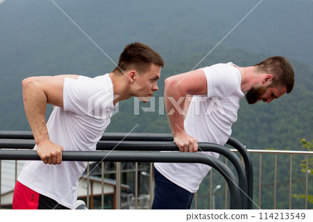 Two sportsmen doing dips on parallel bars Two sportsmen doing dips on parallel bars 114213549