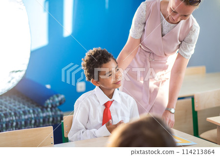 Teacher helping kids with their homework in classroom at school 114213864