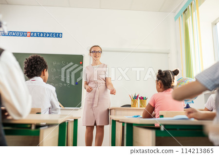 Teacher helping kids with their homework in classroom at school Teacher helping kids with their homework in classroom at school 114213865