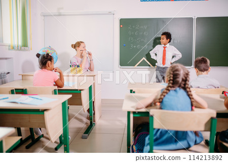 boy solving addition and subtraction on board. schoolboy writing solution of mathematical operation boy solving addition and subtraction on board. schoolboy writing solution of mathematical operation 114213892
