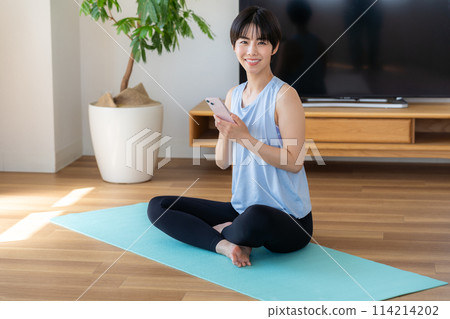 Woman doing yoga in the living room Woman doing yoga in the living room 114214202