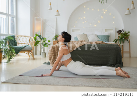 Yoga fitness workout training. Woman practicing yoga at home. Woman doing sports exercise on yoga mat on floor indoor. Girl in sportswear have training workout for weight loss. Sport and fitness 114219115