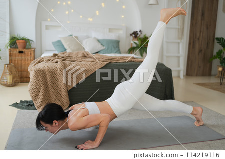 Yoga fitness workout training. Woman practicing yoga at home. Woman doing sports exercise on yoga mat on floor indoor. Girl in sportswear have training workout for weight loss. Sport and fitness Yoga fitness workout training. Woman practicing yoga at home. Woman doing sports exercise on yoga mat on floor indoor. Girl in sportswear have training workout for weight loss. Sport and fitness 114219116