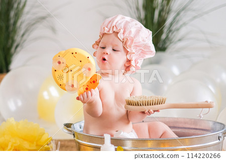 Bath time for baby, child sitting in a basin with rubber ducks 114220266