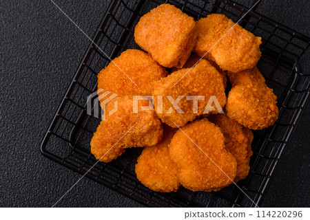 Delicious fresh crispy chicken nuggets on a dark concrete background Delicious fresh crispy chicken nuggets on a dark concrete background 114220296
