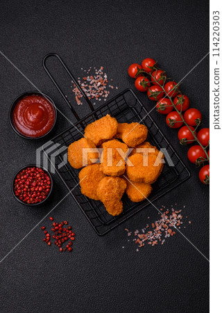Delicious fresh crispy chicken nuggets on a dark concrete background 114220303