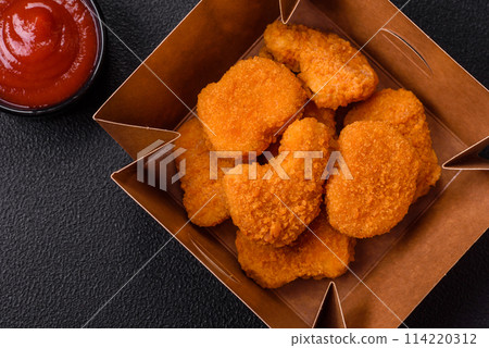 Delicious fresh crispy chicken nuggets on a dark concrete background 114220312