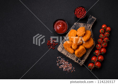 Delicious fresh crispy chicken nuggets on a dark concrete background 114220317