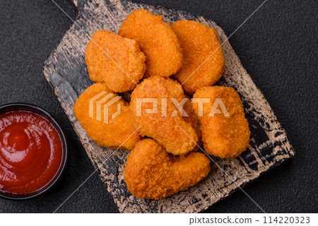Delicious fresh crispy chicken nuggets on a dark concrete background 114220323