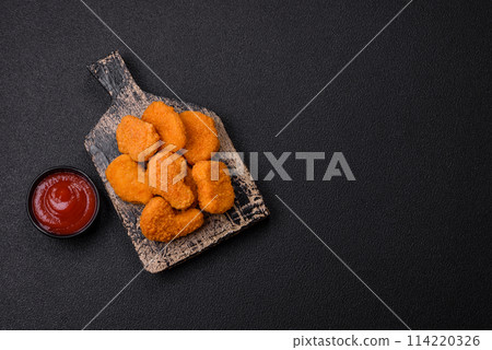 Delicious fresh crispy chicken nuggets on a dark concrete background 114220326