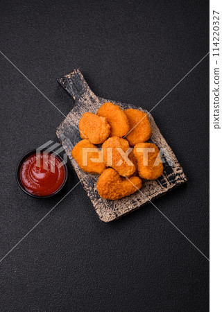 Delicious fresh crispy chicken nuggets on a dark concrete background Delicious fresh crispy chicken nuggets on a dark concrete background 114220327