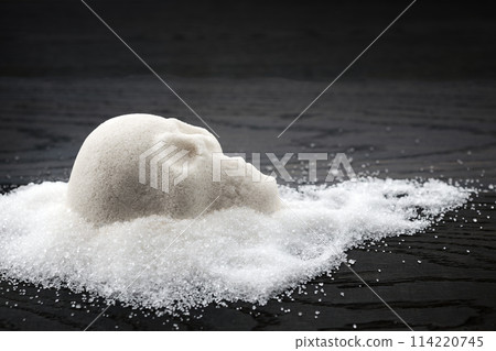 A skull-shaped sugar mound on a wooden surface symbolizing the concept of unhealthy diet 114220745