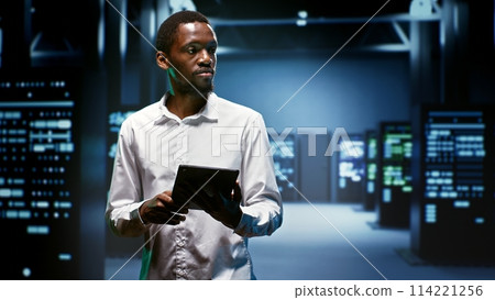 Smiling technician doing checkup in server room providing vast computing resources and storage, enabling artificial intelligence to process massive datasets for training and inference 114221256