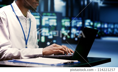 Engineer preventing strain on data center infrastructure caused by artificial intelligence applications driving up power usage. African american expert maintenancing servers doing intense computations 114221257