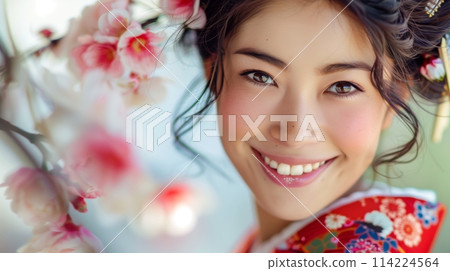 A close-up of a Japanese woman wearing a kimono, smiling with cherry blossoms in the background A close-up of a Japanese woman wearing a kimono, smiling with cherry blossoms in the background 114224564