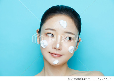 Young woman photographed against a blue background with texture of cosmetics 114225392
