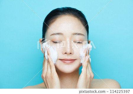 在藍色背景下拍攝的年輕女性的化妝品質感 在藍色背景下拍攝的年輕女性的化妝品質感 114225397