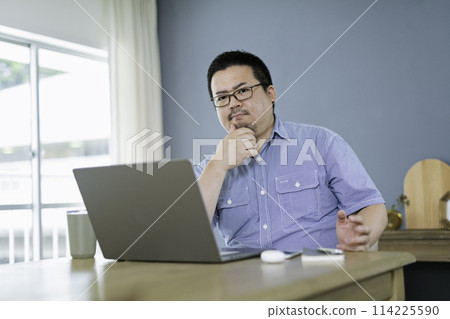 A large Japanese man thinking while working remotely A large Japanese man thinking while working remotely 114225590