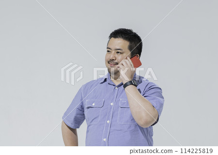 一個大個子的日本男人用智慧型手機打電話 114225819