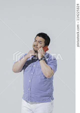 一位身材高大的日本男子在電話中疑惑不已。 一位身材高大的日本男子在電話中疑惑不已。 114225824