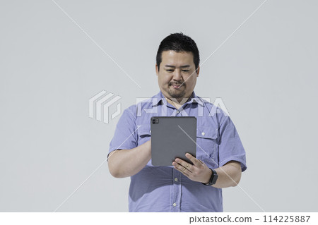 一個大個子的日本男人使用平板電腦設備 一個大個子的日本男人使用平板電腦設備 114225887