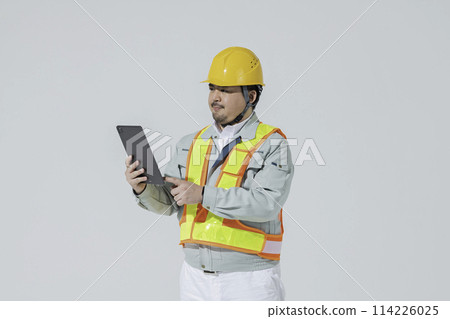 A man in work clothes looking at a tablet A man in work clothes looking at a tablet 114226025