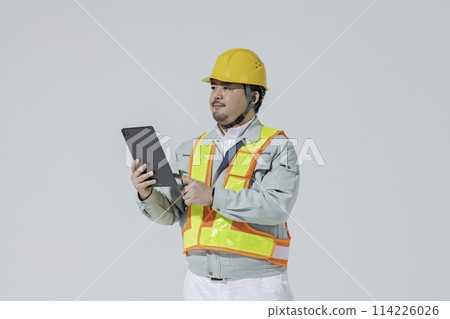 A man in work clothes looking at a tablet 114226026