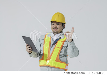 A man in work clothes holding a tablet device and making an OK sign 114226033