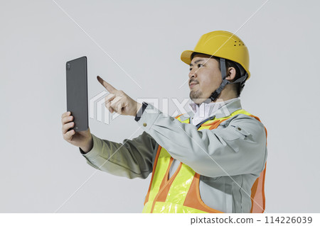 一名穿著工作服的男子一邊看著平板電腦一邊給予指示 114226039