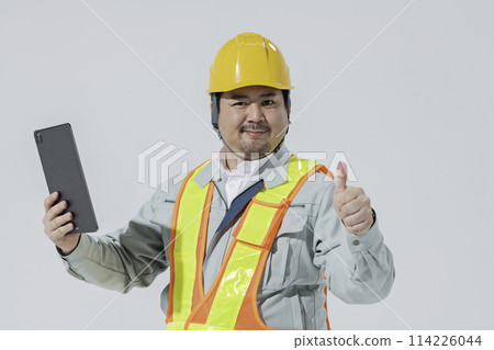 A man in work clothes holding a tablet device and giving a thumbs up A man in work clothes holding a tablet device and giving a thumbs up 114226044