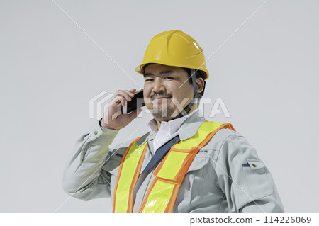A man in work clothes making a phone call on his smartphone 114226069