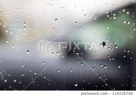 Electric blue rain drops on glass with blurry sky background Electric blue rain drops on glass with blurry sky background 114226748