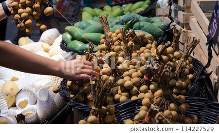 Close-up of woman choosing fresh lychee fruit at grocery store. Tropical fruits concept Close-up of woman choosing fresh lychee fruit at grocery store. Tropical fruits concept 114227529