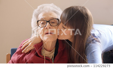 Granddaughter embracing and kissing her grandmother in a geriatric 114229273