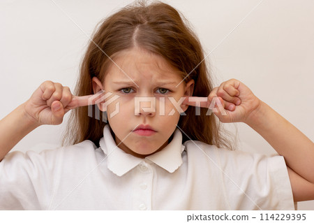 Portrait of caucasian child close ears by fingers on white background Portrait of caucasian child close ears by fingers on white background 114229395