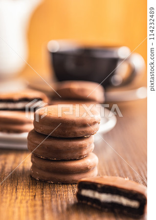 Close-Up View of Chocolate-Coated Sandwich Cookies on wooden table. Close-Up View of Chocolate-Coated Sandwich Cookies on wooden table. 114232489