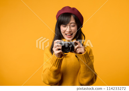 With her camera in hand, a young Asian woman, a skilled photographer, travels the world in her yellow sweater and red beret, preserving beautiful moments in time. With her camera in hand, a young Asian woman, a skilled photographer, travels the world in her yellow sweater and red beret, preserving beautiful moments in time. 114233272