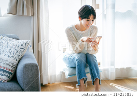 在房間裡操作智能手機的女人 114235833
