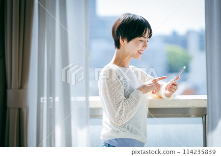 A woman who operates a smartphone in the room A woman who operates a smartphone in the room 114235839