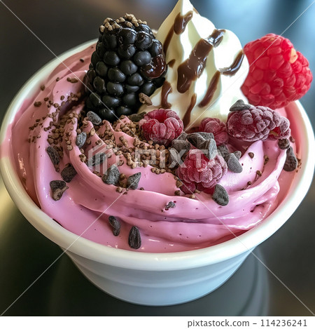 Velvety pink frozen yogurt topped with berries and chocolate bits. 114236241