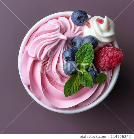Soft, swirled pink and white frozen yogurt or ice cream topped with fresh berries and mint. 114236243