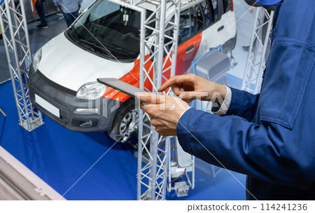 Serviceman with digital tablet on the background of the car in the car service.. Serviceman with digital tablet on the background of the car in the car service.. 114241236