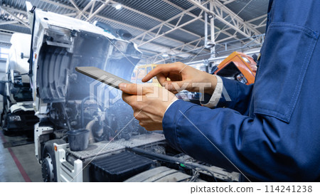 Serviceman with digital tablet on the background of the truck in the garage. Serviceman with digital tablet on the background of the truck in the garage. 114241238