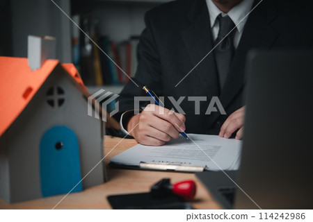professional real estate agent signs documents or contracts authorizing the purchase of a home. Insurance or home legal agreements professional real estate agent signs documents or contracts authorizing the purchase of a home. Insurance or home legal agreements 114242986