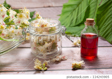 The extract of the flower of chestnut and chestnut flower isolated on a wooden background. Hairloss concept. Close up The extract of the flower of chestnut and chestnut flower isolated on a wooden background. Hairloss concept. Close up 114243905