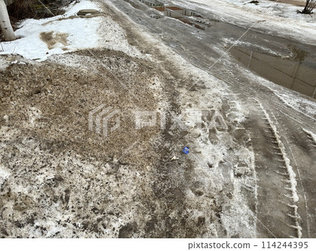 Melting dirty snow on the streets of the city during the daytime in winter. Snow with sand and mud lies on the road. Melting dirty snow on the streets of the city during the daytime in winter. Snow with sand and mud lies on the road. 114244395