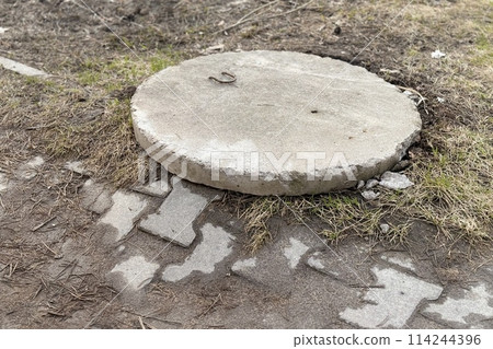 Concrete manhole above an observation well is located next to pedestrian road during the daytime 114244396